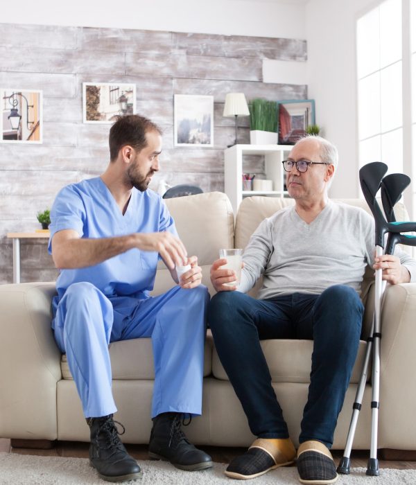 young-male-nurse-in-nursing-home-with-pills-for-senior-man.jpg